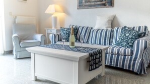 A living room with a striped sofa, a white armchair, a coffee table, and a lamp. - Vacation home on the Bodden near Fischland-Darß-Zingst; fenced-in garden. Dogs Welcome (Pruchten)