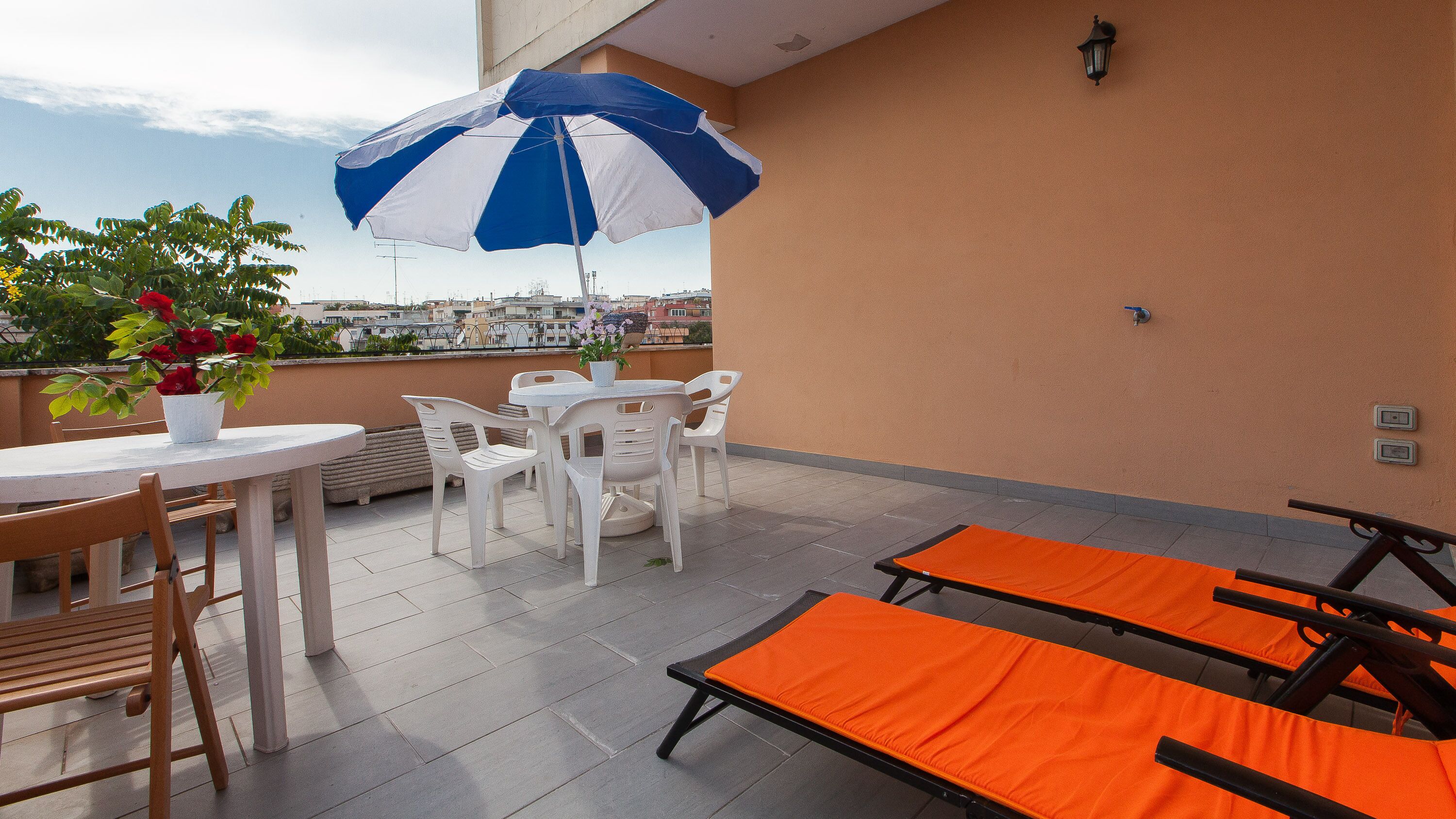 Una terrazza con tavolo, sedie, ombrellone e poltrone relax.