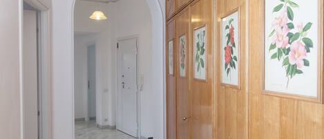 A hallway with wooden paneling and framed botanical prints on the wall.