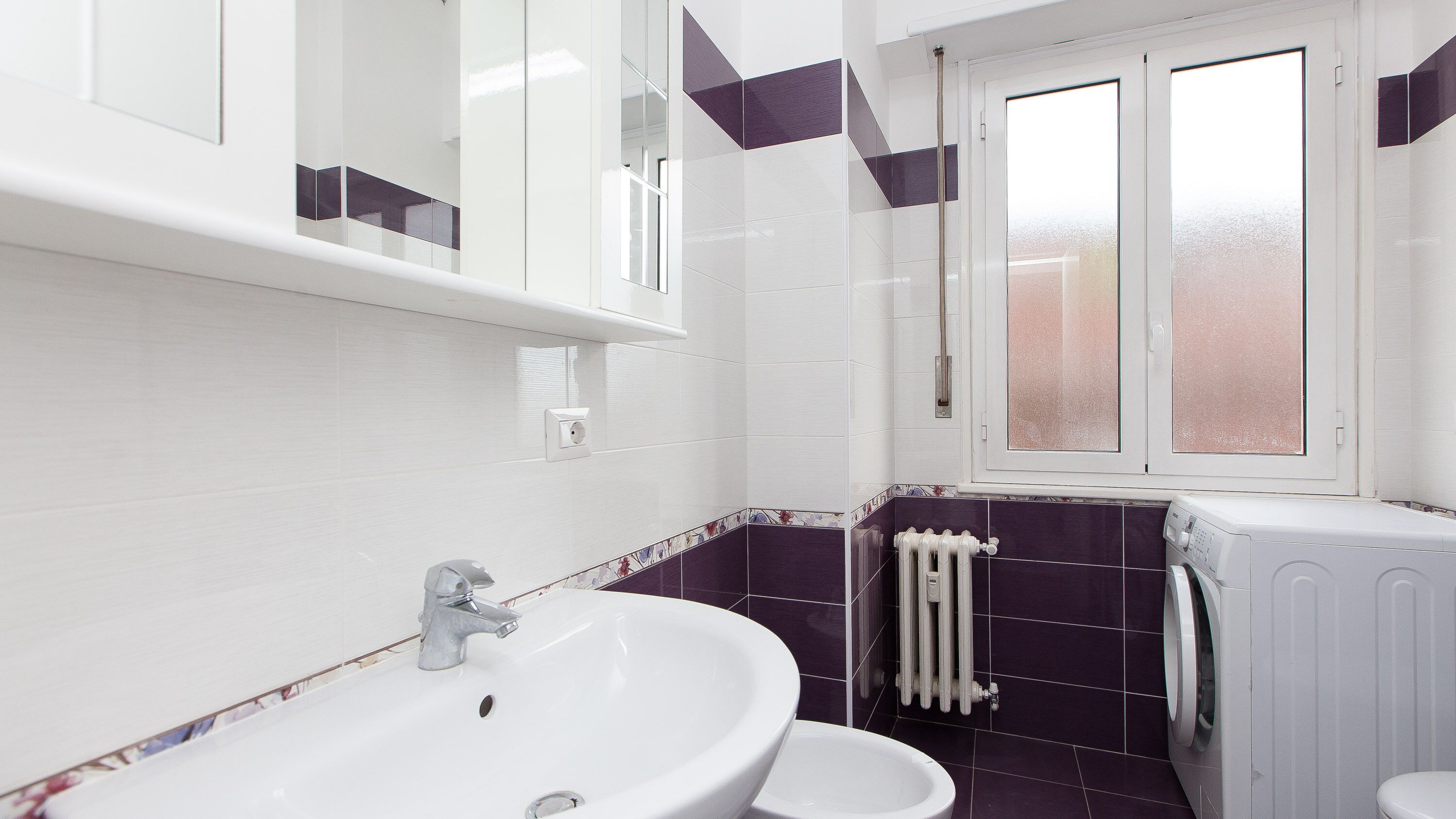 A bathroom with a white sink, a toilet, and a window.