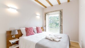 Ein Schlafzimmer mit Bett, Nachttisch, Lampe und einem Fenster mit Blick.