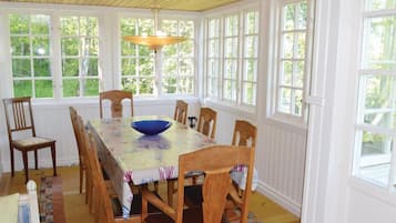 Une salle à manger avec une grande table, six chaises en bois, un bol bleu et un luminaire suspendu.