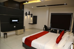 Quarto de hotel moderno com uma cama grande, televisão de tela plana na parede, escrivaninha com cadeira e uma janela ampla.