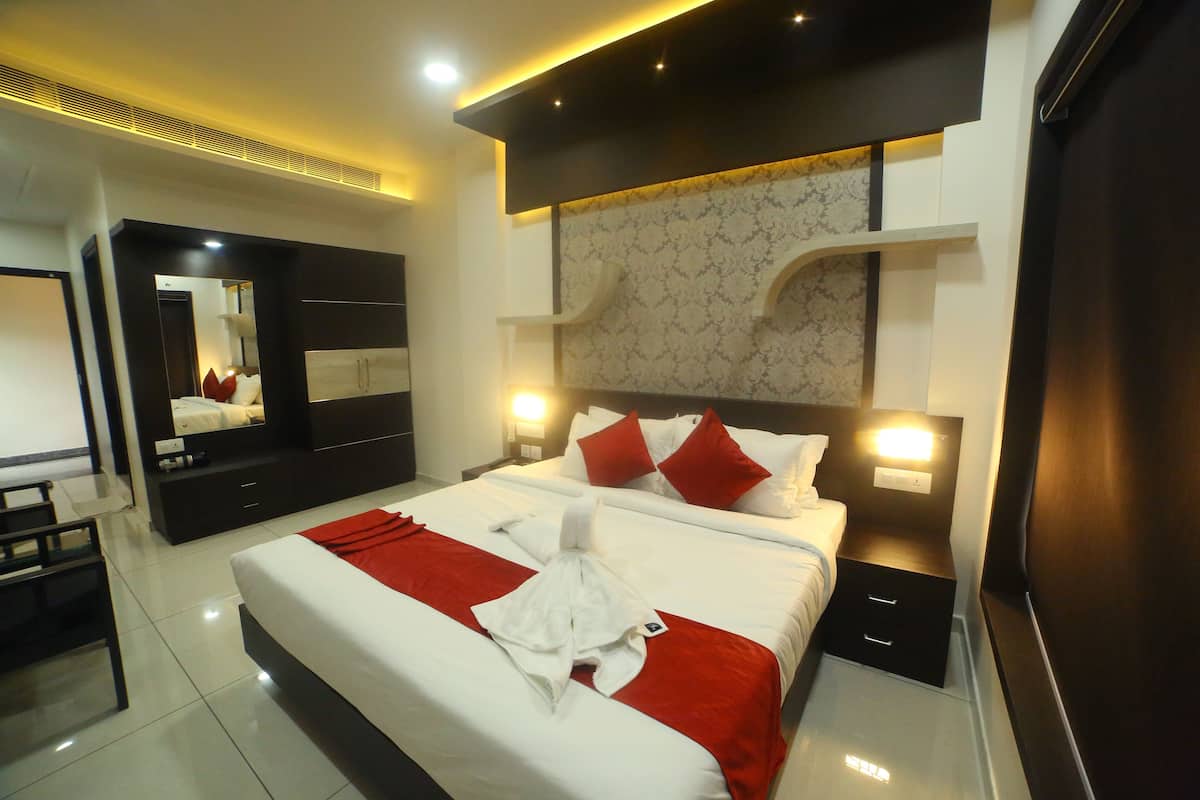 A modern hotel room with a large bed, a wardrobe, a desk, and a mirror.