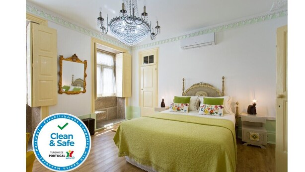 Een slaapkamer met een bed, nachtkastjes, een spiegel en een kroonluchter.