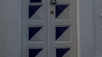 A white door with blue triangular patterns and a brass knocker.