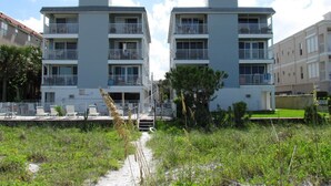 A modern apartment building with multiple balconies and a pathway leading to a gated entrance. - Family Favorite Sea Isles- Indian Rocks Beachfront and Sunsets Galore!! (Indian Rocks Beach)