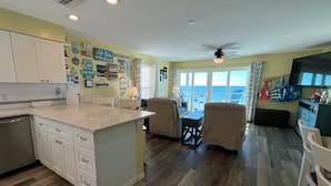 A kitchen with a central island, white cabinets, and a dining area with a table and chairs. - Family Favorite Sea Isles- Indian Rocks Beachfront and Sunsets Galore!! (Indian Rocks Beach)
