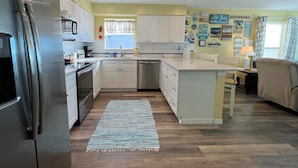 A modern kitchen with white cabinets, a stainless steel refrigerator, a dishwasher, and a central island. - Family Favorite Sea Isles- Indian Rocks Beachfront and Sunsets Galore!! (Indian Rocks Beach)