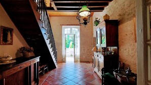 Ein schmales Entree mit Treppe an einer Seite, einer Tür zu einem hellen Raum und einem Schrank mit Dekorationselementen auf der anderen Seite.