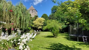 Ein Garten mit einem Steinhaus, weißen Blüten und einem Trampolin.