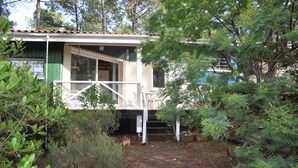 Un chalet rustique doté d’un porche, entouré d’une végétation luxuriante et d’arbres.