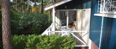 Una cabaña con porche, rodeada de un bosque denso.