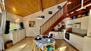 Une cuisine compacte avec un coin repas, un plafond en bois et un escalier menant à un niveau supérieur.
