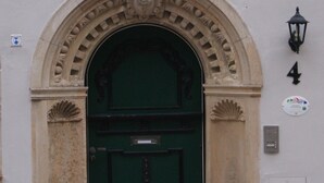 Ein Gebäudeeingang mit einer grünen Tür, einem Bogen und einem Schild mit der Aufschrift 'Ginflehr'.