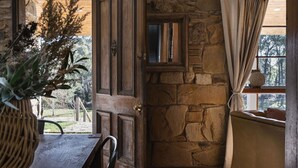 Un mur de pedra, una porta de fusta i una finestra amb cortines.