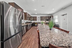 A modern kitchen with stainless steel appliances, dark wood cabinets, and a granite countertop. - Luxury Resort HOME: 14BR Large Group Rental 0.1mile to Beach-EXCLUSIVE AMENITIES (North Myrtle Beach)