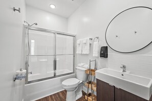 Een bad/douchecombinatie, handdoeken, zeep, toiletpapier