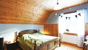 A bedroom with a wooden ceiling, a bed with a green blanket, a nightstand, a dresser, and a window with curtains. - 2 bedroom beautiful home in Mellerud (Mellerud)
