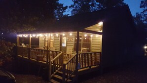 Une cabane dotée d’un porche, d’une terrasse en bois et de guirlandes lumineuses.