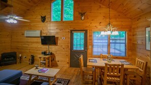 Un chalet confortable avec un coin repas, un téléviseur et une cheminée.