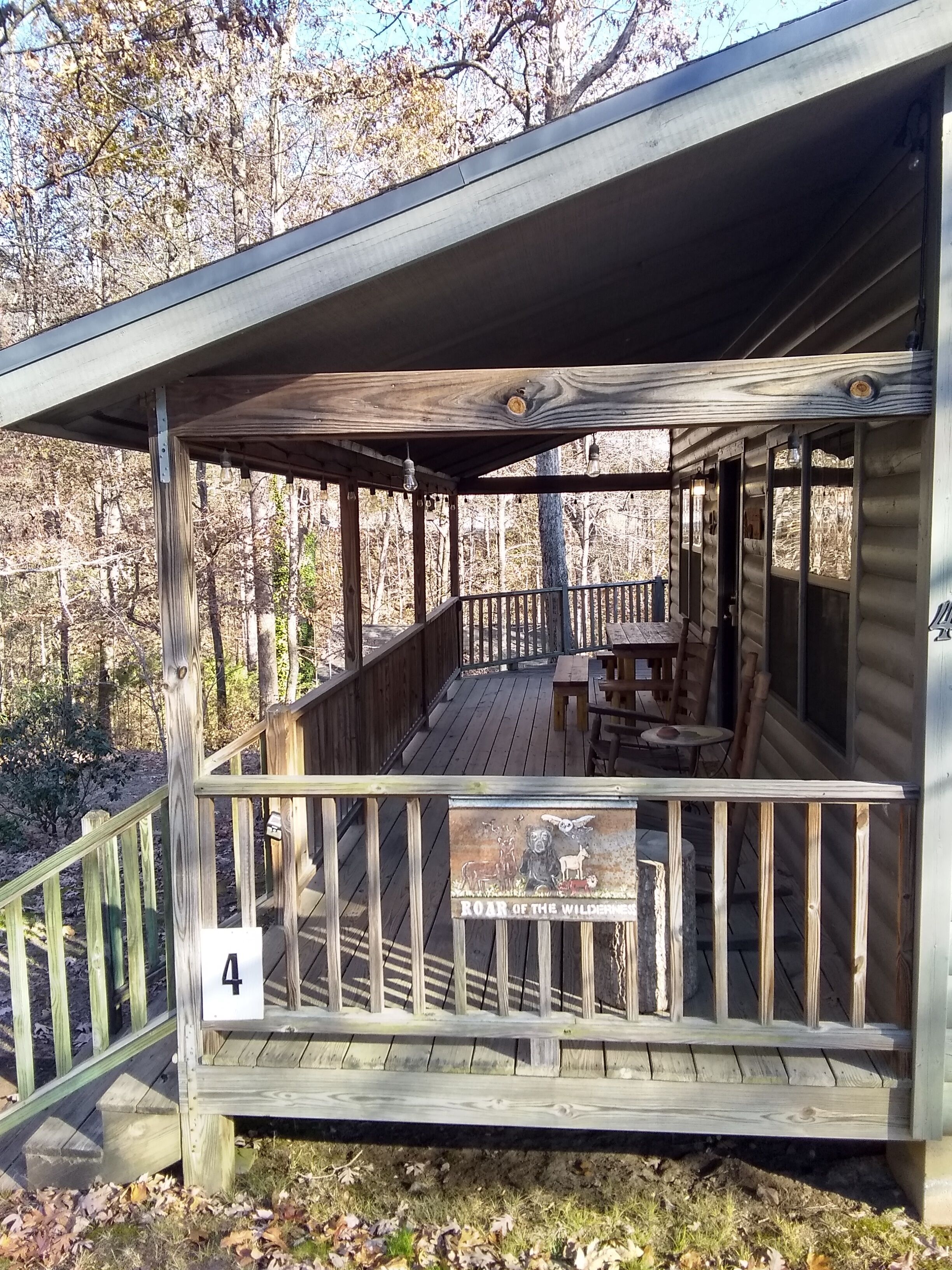 A wooden cabin with a porch, a table, and benches.