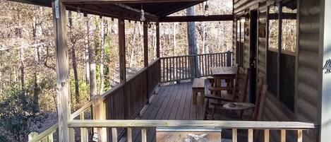 A wooden cabin with a porch, a table, and benches.