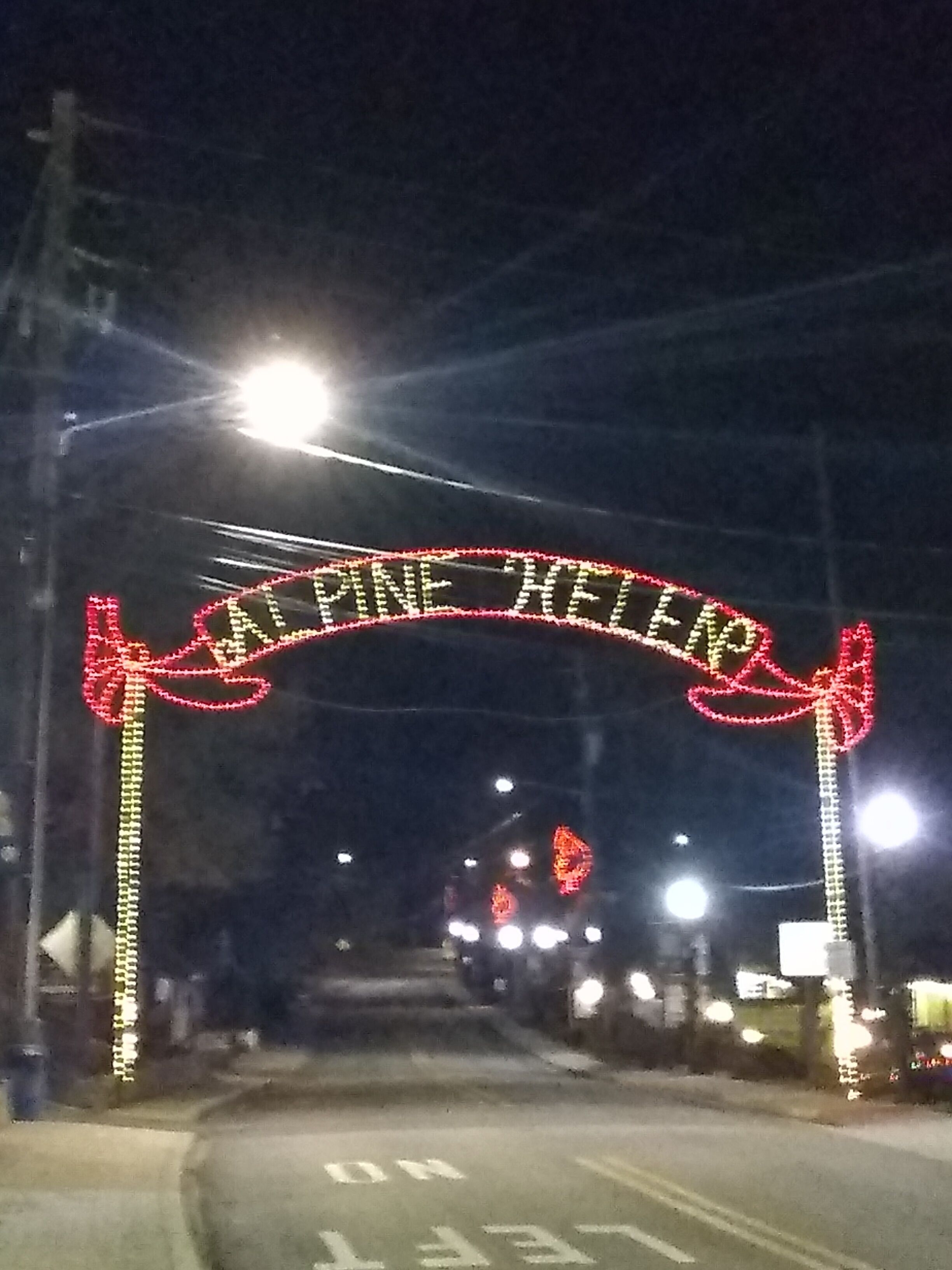 A street sign with the text "Pine Hollow" illuminated by lights.
