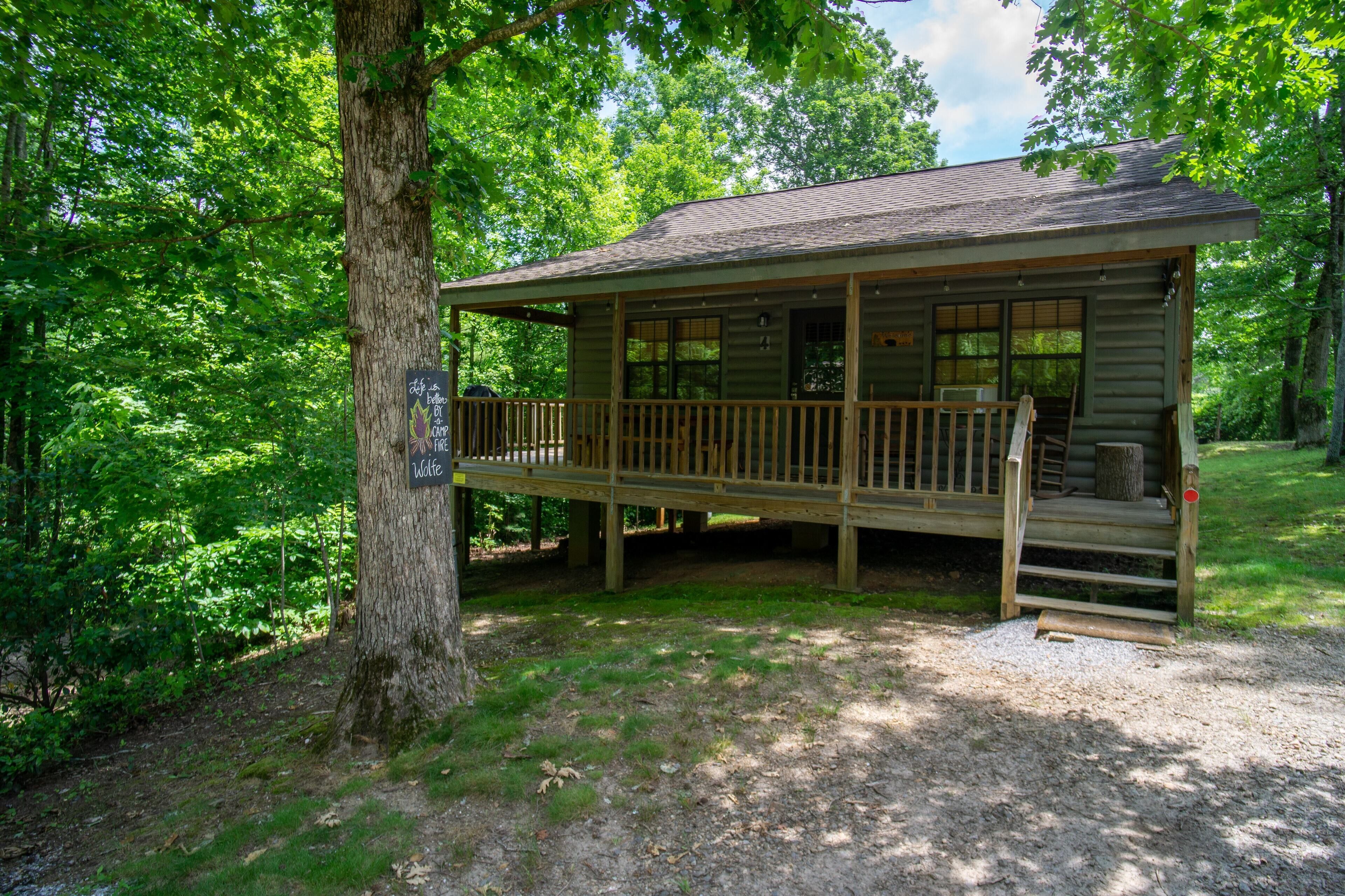 A cabin with a deck, surrounded by trees.
