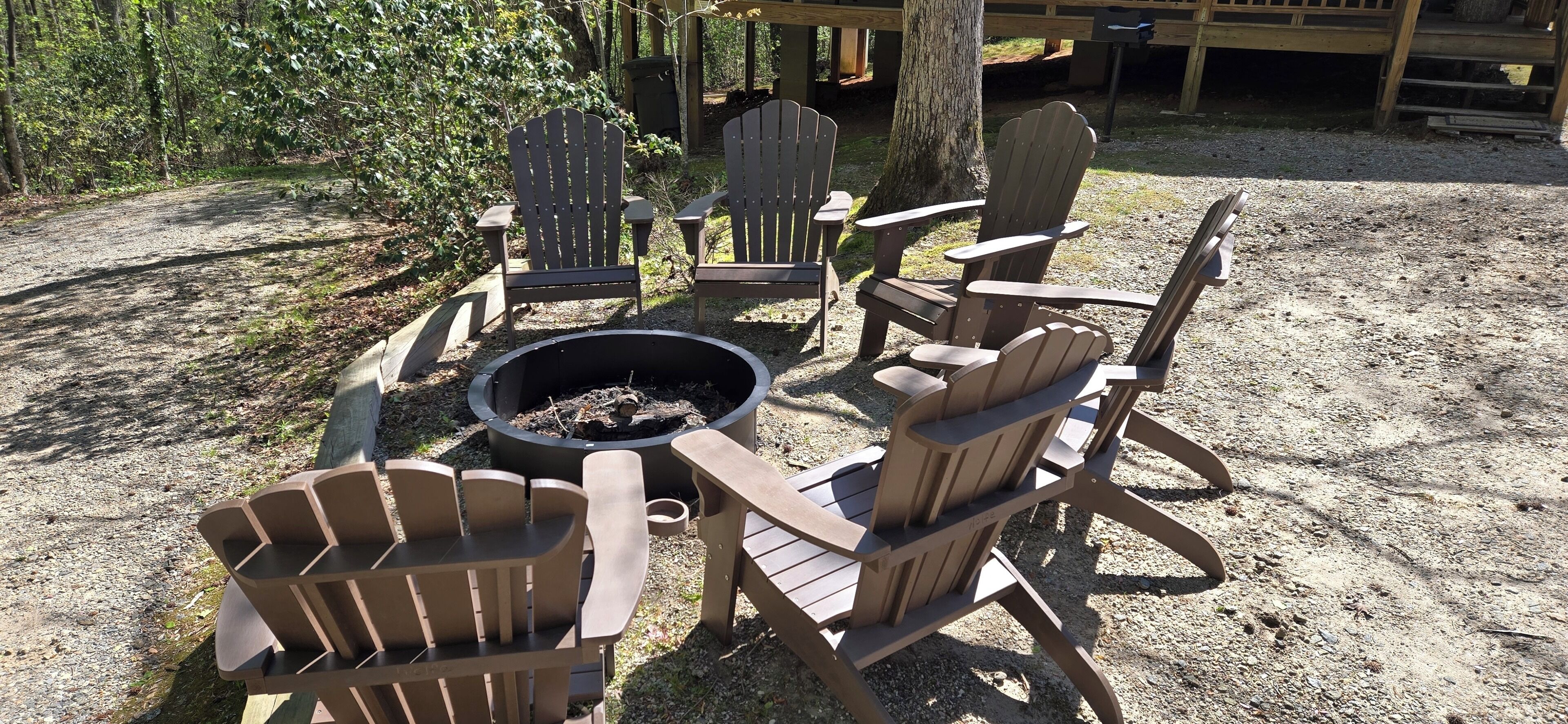 A circular seating arrangement with Adirondack chairs around a central fire pit.
