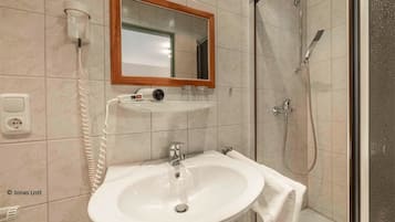 Ein Badezimmer mit Waschbecken, Spiegel, Föhn und Dusche.