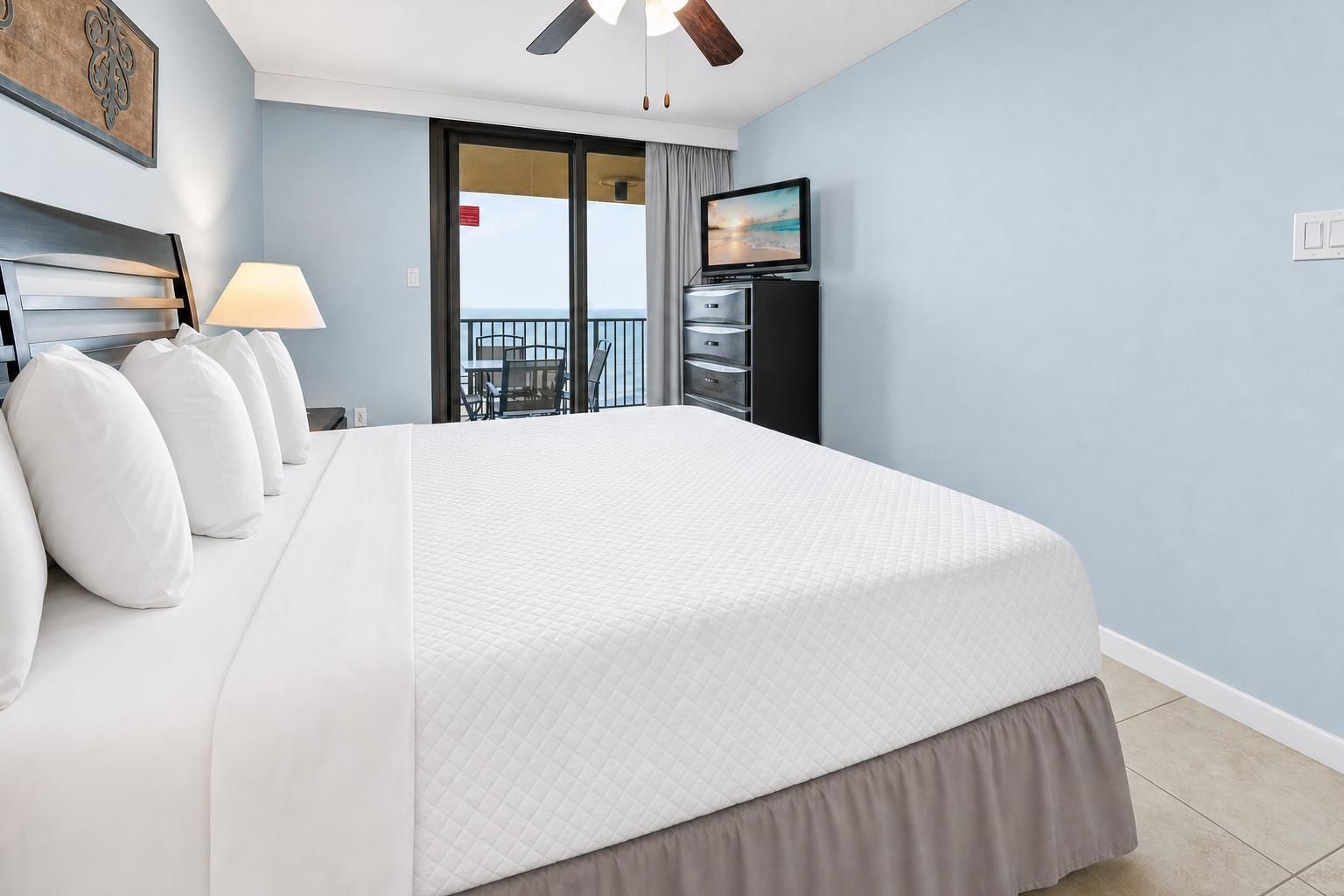 Una habitación de hotel con una cama grande, televisión, escritorio y balcón con vistas.
