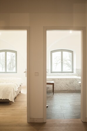 A bedroom with a bed, a nightstand, and a window with a view of trees.