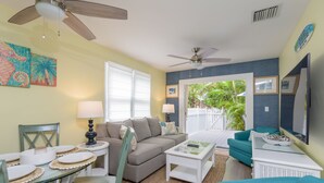 Ein Wohnzimmer mit einer Couch, einem Couchtisch, einem Esstisch mit Tellern und einem Deckenventilator.