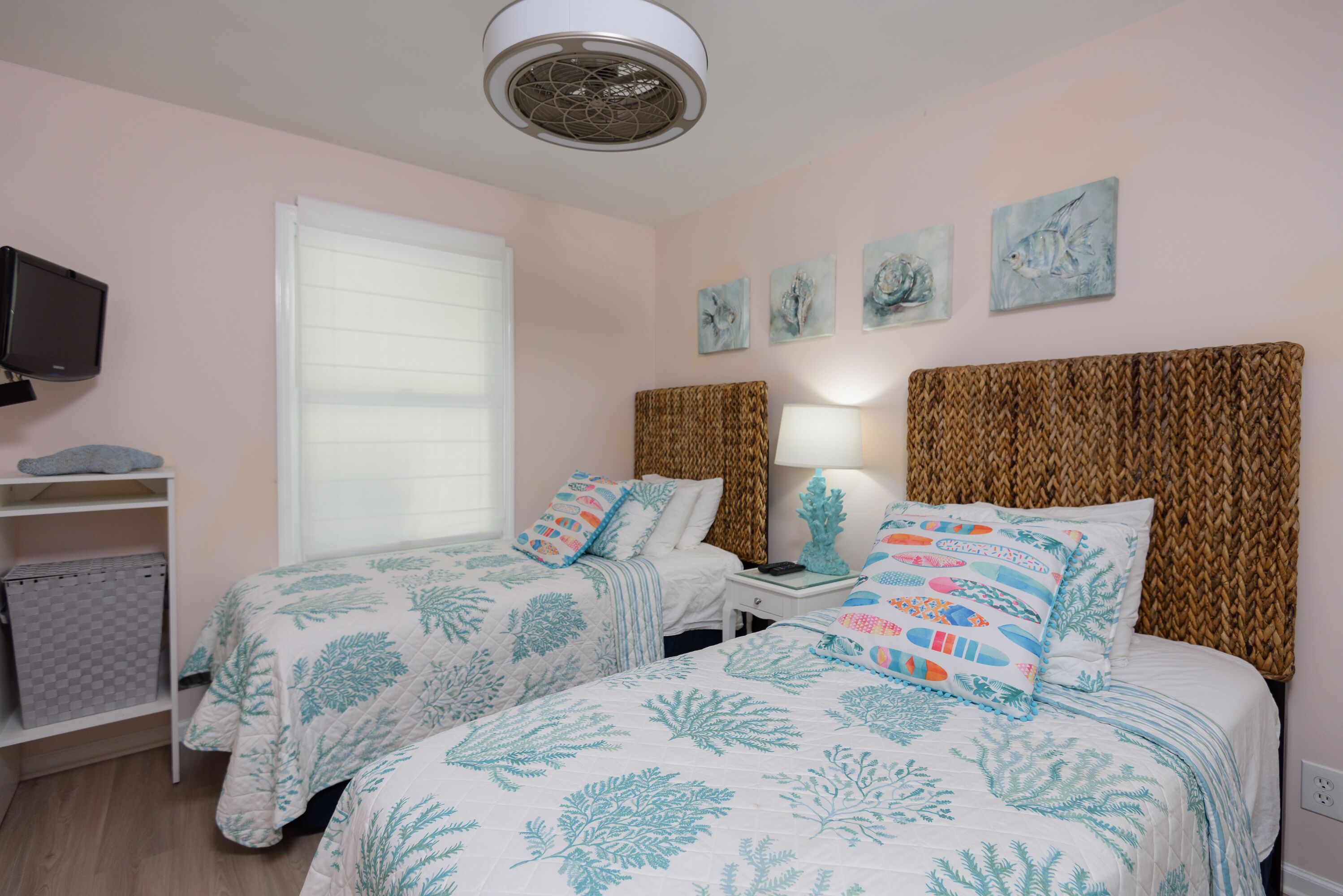 A bedroom with two beds, a television, and artwork on the wall.
