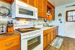 Une cuisine avec des meubles de rangement en bois, une cuisinière, un four à micro-ondes et un grille-pain.