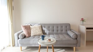 A modern living room with a grey sofa, a small round table, and a decorative vase on a cabinet.