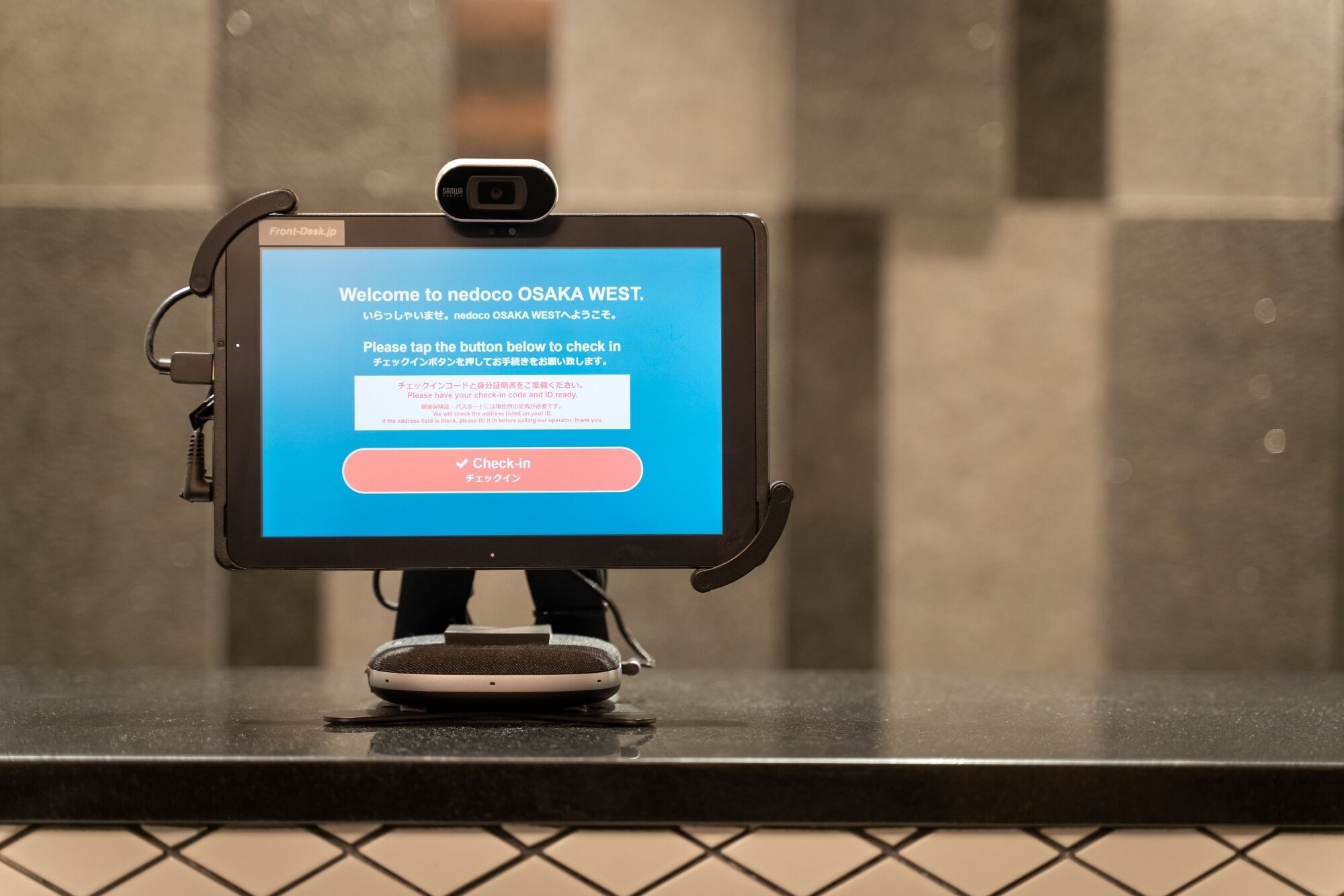 Quiosco de autoservicio con una pantalla que muestra un mensaje de bienvenida y un botón de registro.