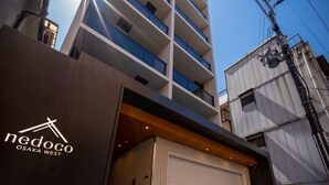 A modern building with a large garage door, a logo with a stylized 'N' and 'O', and a clear sky.