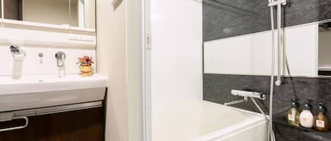Un baño moderno con bañera, ducha y tocador con espejo.