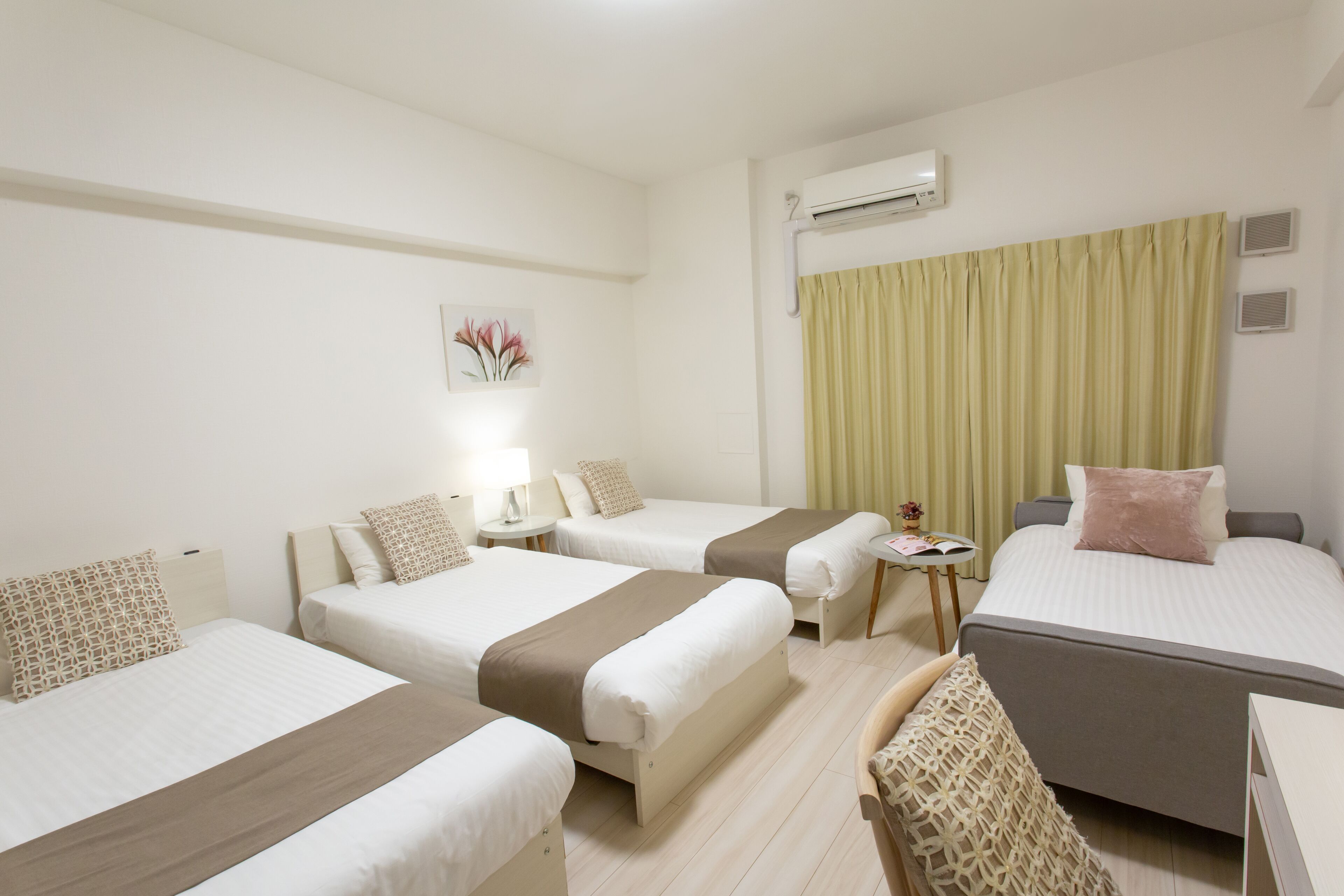Une chambre d’hôtel avec deux lits simples, un canapé-lit, une petite table et une chaise.