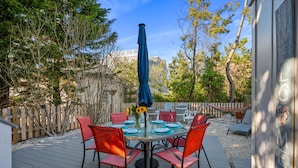 An outdoor patio with a round table, red chairs, and a blue umbrella.