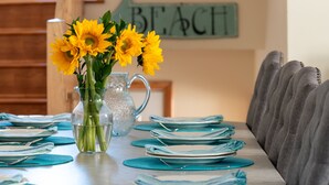 A dining table set with blue placemats and plates, a clear glass pitcher with water, and a vase with yellow flowers.