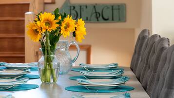 A dining table set with blue placemats and plates, a clear glass pitcher with water, and a vase with yellow flowers.