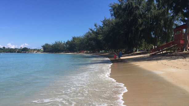 A beach with clear water, a sandy shore, and a red structure. - PENTHOUSE CONDO | BEAUTIFUL | 3 BEDS | 3 BATHS | 2 LEVELS | MAGNIFICENT VIEWS (Fajardo)