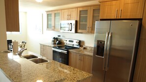 A modern kitchen with granite countertops, stainless steel appliances, and wooden cabinets. - PENTHOUSE CONDO | BEAUTIFUL | 3 BEDS | 3 BATHS | 2 LEVELS | MAGNIFICENT VIEWS (Fajardo)