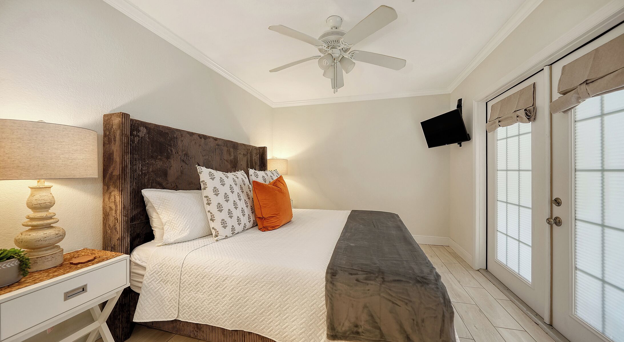 A bedroom with a bed, bedside table, lamp, and a ceiling fan.