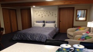 Een slaapkamer met een bed, een stoel, een tafel en een spiegel.