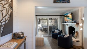 Ein Wohnzimmer mit Kamin, Fernseher und Blick ins Freie.