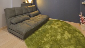A modern living room with a grey sofa, a green shag rug, and a flat-screen TV mounted on the wall. - Merveille Ueno House Tokyo (Tokyo)
